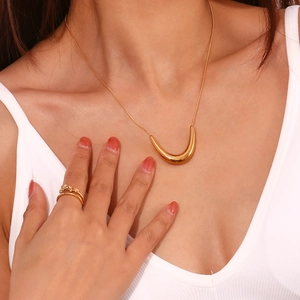Detailed view of 18K gold plated V-shape pendant necklace and leaf ring on a model