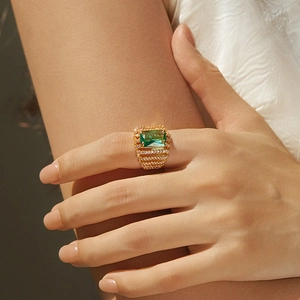 Detailed close-up of a wide 18K gold ring featuring a large green emerald zircon and crystals
