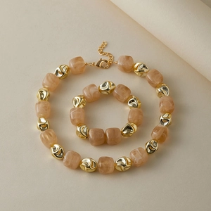 Dettaglio del set di collane con perle in resina marmorizzata rosa e grani dorati