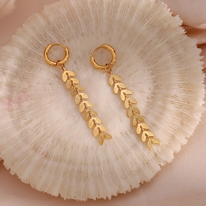 Close-up of 18K gold-plated long leaf chain earrings on a white coral texture tray