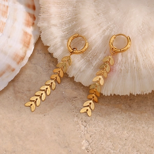 Macro shot of gold leaf chain earrings on a shell, showing detailed cascading metal leaves