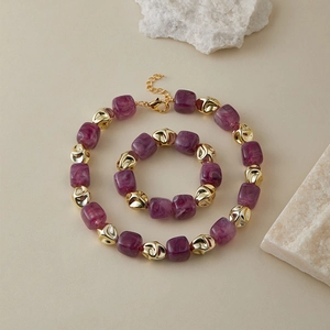 Dettaglio del set di gioielli con perle in resina viola marmorizzata e perle dorate
