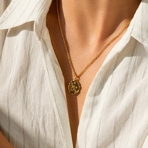 Detail of 18K gold-plated necklace with a butterfly and star engraved coin pendant