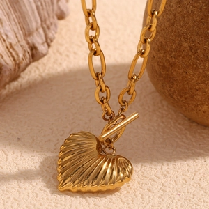 Detailed shot of gold heart pendant with radial textures and toggle clasp on oval link chain
