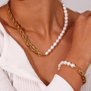 Detailed view of women wearing gold twist chain and white freshwater pearl necklace jewelry
