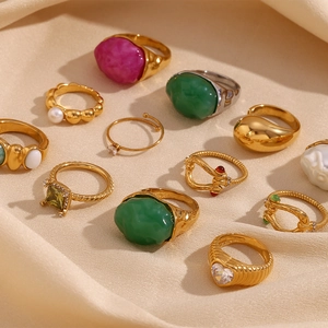 Detailed close-up of 18K gold plated rings with colorful resin stones on silk fabric