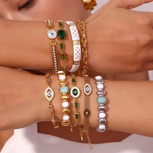 Detail von böhmischen 18K Gold Armbändern mit bösem Blick und Smaragdsteinen am Handgelenk