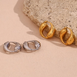 Detailed close-up of gold and silver polished water drop hoop earrings on a stone base