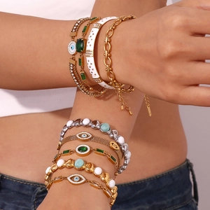 Nahaufnahme kombinierter 18K vergoldeter Evil Eye Armbänder mit grünen Steinen und Perlen