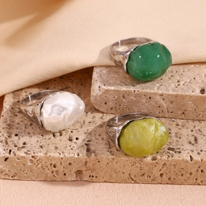Detail of three 18K gold plated wavy rings with colorful resin stones on stone base