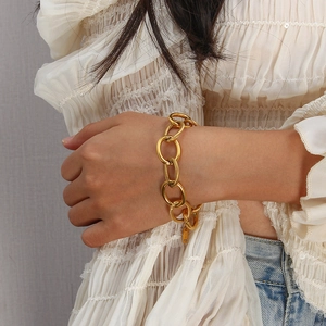 Bracciale a catena dorata grossa con trama a spirale su modella con top in pizzo