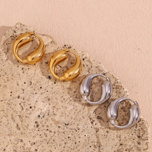 Close-up of gold and silver teardrop hoop earrings with a polished mirror finish