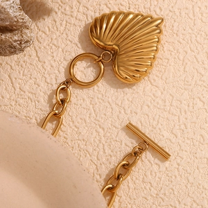 Macro detail of 18K gold-plated chunky chain bracelet with textured heart pendant and OT clasp