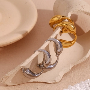 Detailed view of water drop earrings in gold and silver finish on a ceramic base