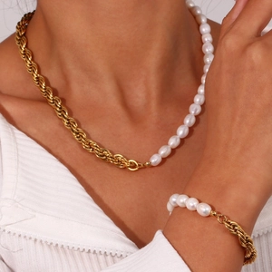Close-up of model wearing asymmetrical freshwater pearl and gold chain necklace and bracelet