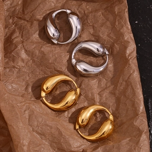 Polished 18K gold and silver teardrop interlocking hoop earrings on craft paper