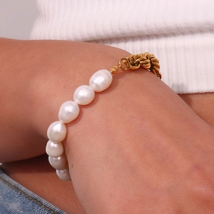 Close-up of a gold Cuban chain bracelet featuring natural baroque pearls worn on wrist