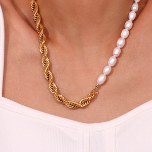 Detail of a gold rope chain and freshwater pearl necklace worn on the neck
