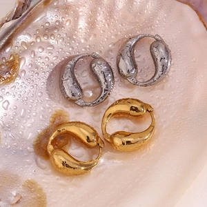 Detailed close-up of water droplet gold and silver earrings on a shimmering shell surface