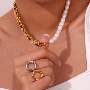 Close-up of a split freshwater pearl and gold chain necklace with geometric rings