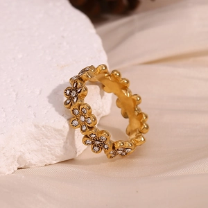 Vue macro d'une bague marguerite dorée sertie de cristaux sur pierre blanche et satin