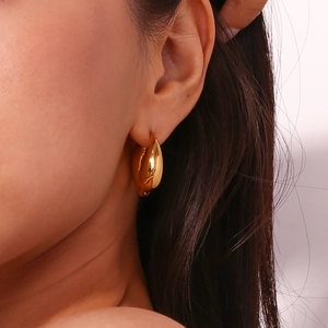 Close-up of polished 18K gold-plated stainless steel teardrop hoop earrings on model