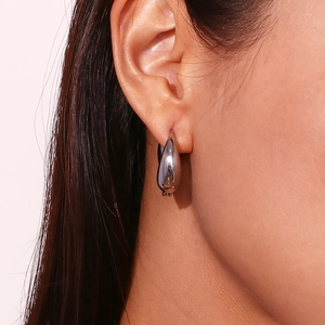 Detailed close-up of a silver-toned polished teardrop hoop earring on a female model