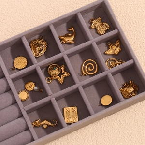 Detailed close-up of 18K gold-plated stainless steel animal and celestial pendants on velvet