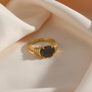 Détail d'une bague vintage dorée avec pierre noire ovale et texture plissée sur soie