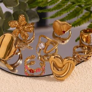 Detailed view of assorted 18K gold plated stainless steel rings on a mirror surface