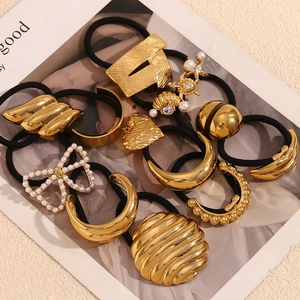 Detailed macro view of 18K gold plated metal charms and pearls on black elastic hair ties