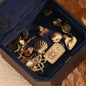 Detailed macro shot of 14K gold plated bee, shell and star charms on blue velvet
