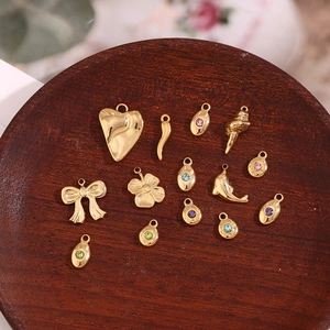 Detailed macro view of 14K gold plated charms with colorful zircon on a wooden tray
