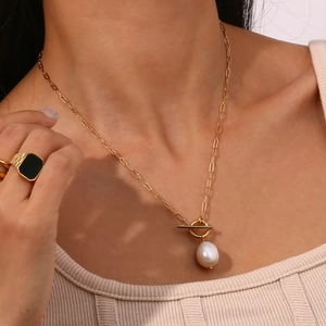 Detalle de collar de cadena tipo clip dorado con perla barroca y cierre de palanca OT