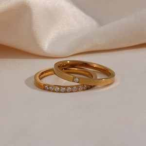 Detail of 18K gold plated stainless steel rings with white zircon inlay on silk background