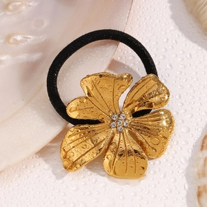 Detailed view of a gold floral hair tie with rhinestones and water droplets on fabric