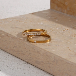 Close-up of 18K gold plated stainless steel rings with zircon inlay on marble base