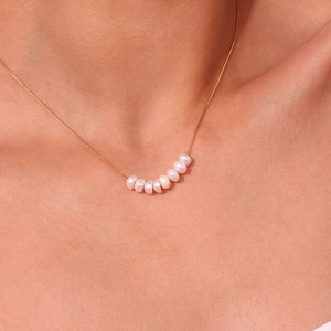 Detalle macro del collar de acero inoxidable en oro 18K con ocho perlas de agua dulce blancas