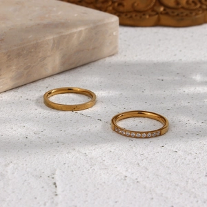 Detailed macro view of two minimalist 18K gold plated stainless steel rings with zircons