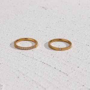 Close-up of dual 18K gold plated rings with cubic zirconia inlay on stone background