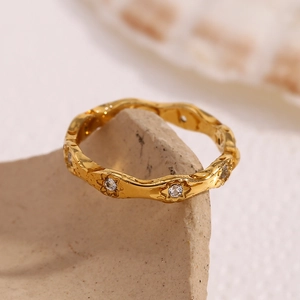 Detailed close-up of 18K gold-plated wavy ring with star engravings and zircon stones