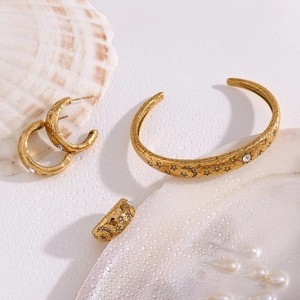Detail of 18K gold plated jewelry set with embossed star and moon celestial motifs