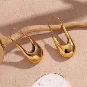Detailweergave van vergulde U-vormige druppeloorbellen met een hoogglanzende spiegelafwerking