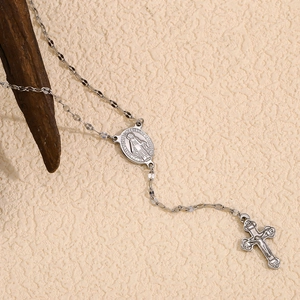 Gros plan détaillé d'un chapelet en argent avec une médaille religieuse et un crucifix