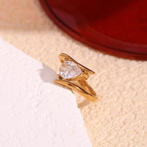 Detail of 18K gold plated wing ring with a drop-shaped cubic zirconia on a stone surface