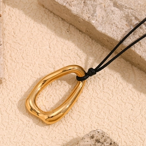 Detail view of a 18K gold-plated irregular ring pendant on a black woven cord necklace