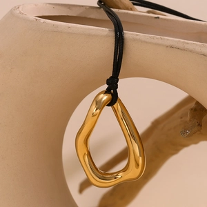 Close-up of a 18K gold plated irregular liquid-metal pendant on a minimalist black cord