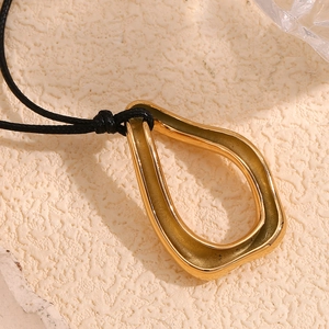 Detail of organic irregular gold-plated drop pendant on a black braided cord necklace
