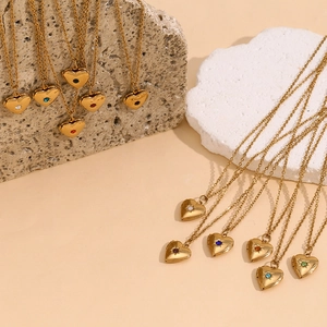 Collection of gold heart locket necklaces with colorful birthstones on stone background