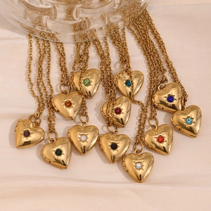 Gold plated heart locket necklaces with various colorful birthstones on silk fabric